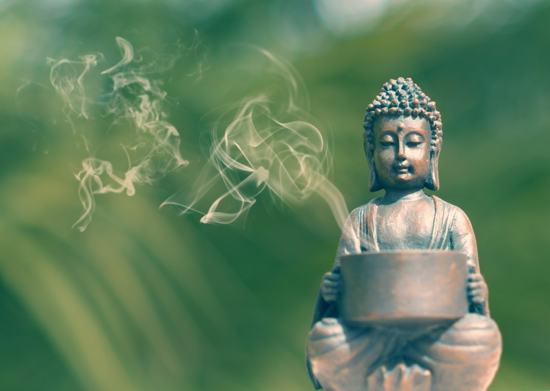 Buddha statue in the grass - meditation pose and incense sticks